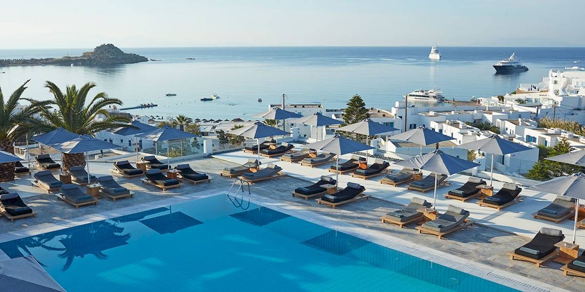 Poolbereich im Myconian Ambassador Relais & Chateaux Hotel mit Sonnenliegen und Blick auf das Meer