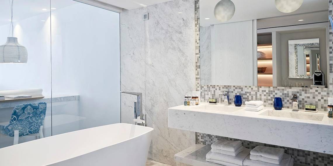 Luxuriöses Badezimmer im Myconian Ambassador Relais & Chateaux mit Badewanne, Doppelwaschbecken und Marmorfliesen.