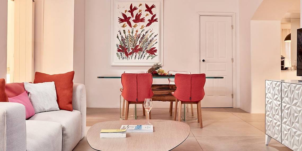 Wohnbereich im Myconian Ambassador Hotel mit Couch, Tisch und Kunstwerk.