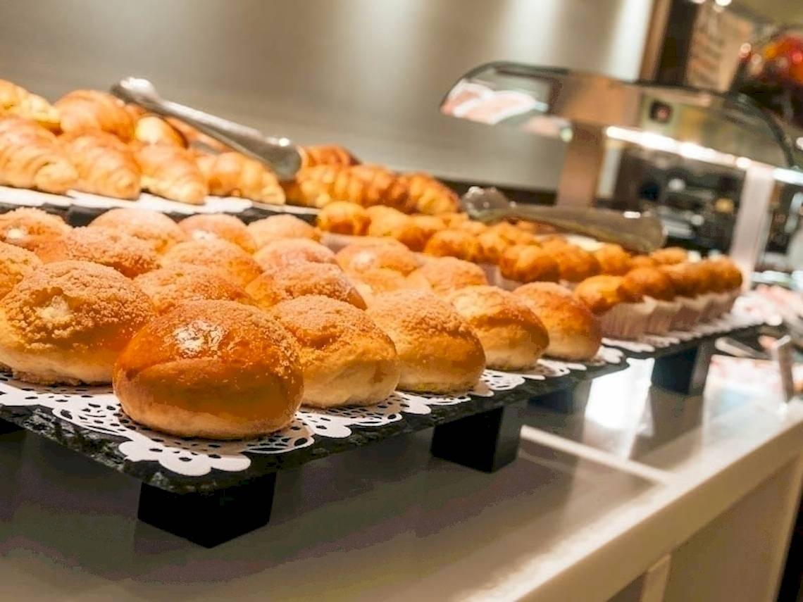 Frühstücksbuffet im Hotel Colonial Barcelona mit verschiedenen Brötchen, Croissants und Muffins.