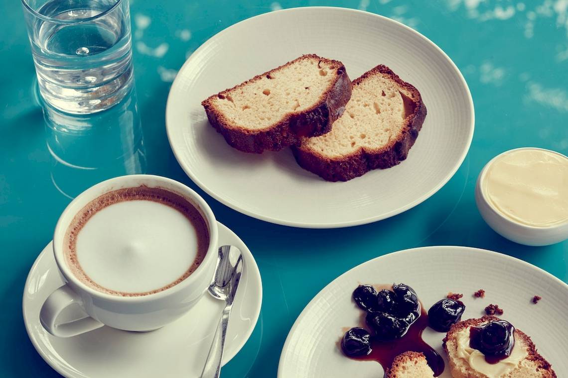 Frühstücksplatte im Myconian Ambassador Hotel mit Kaffee, Toast und Wasser.