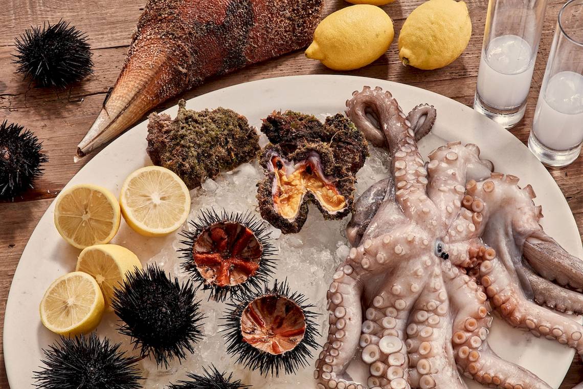 Essen auf Eis mit Oktopus, Seeigeln, Zitronenscheiben und weiteren Meeresfrüchten.