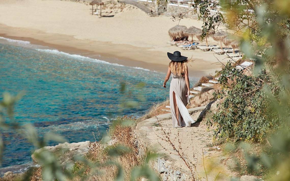 Gast des Myconian Ambassador Relais & Chateaux auf einer Felskante am Strand