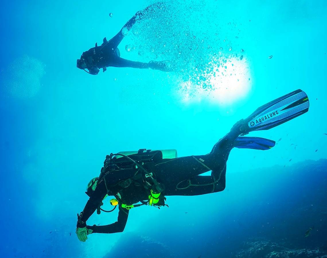 Scuba-Taucher schwimmen im Meer und erkunden die Unterwasserwelt.