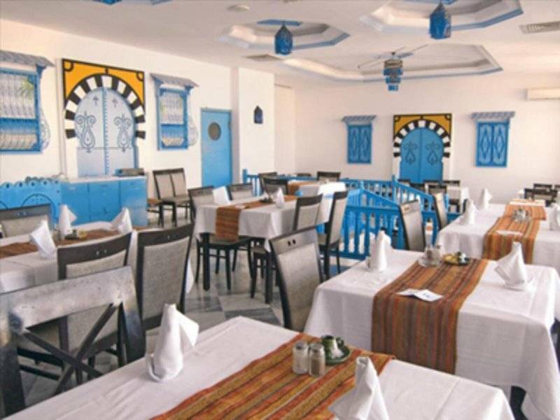 Innenansicht des Restaurants im Djerba Holiday Beach Hotel mit blauen und gelben Wandverzierungen und gepolsterten Stühlen.