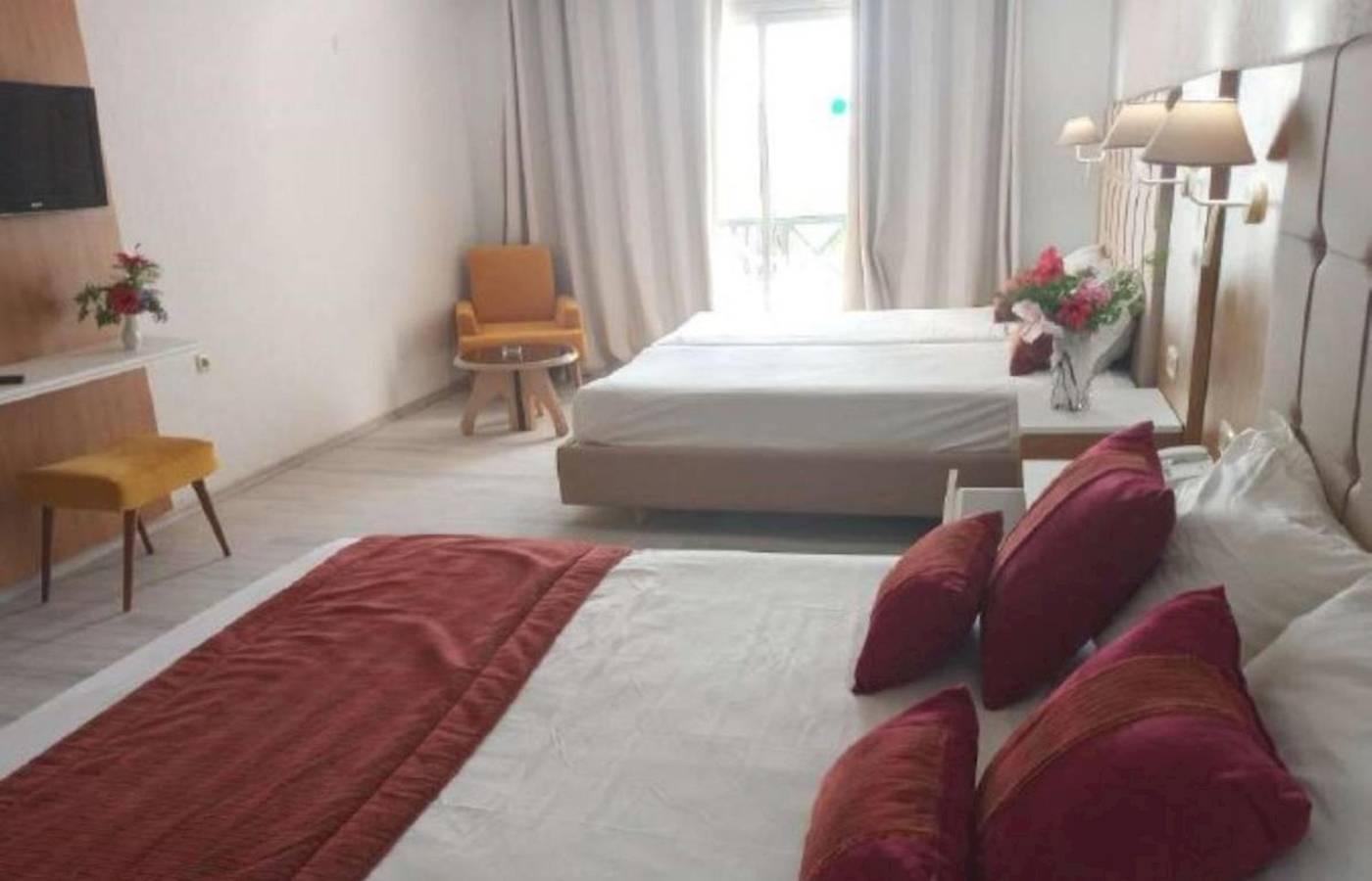 Zwei Betten in einem Hotelzimmer im Djerba Holiday Beach Hotel mit roten Kissen und weißem Laken.