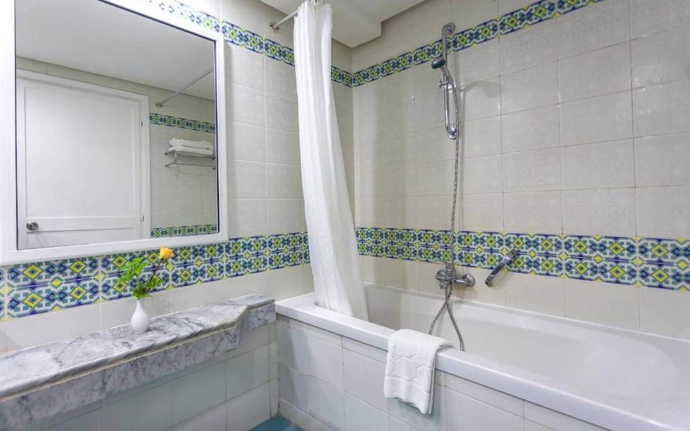 Badezimmer im Djerba Holiday Beach Hotel mit Badewanne, Spiegel und Waschbecken.