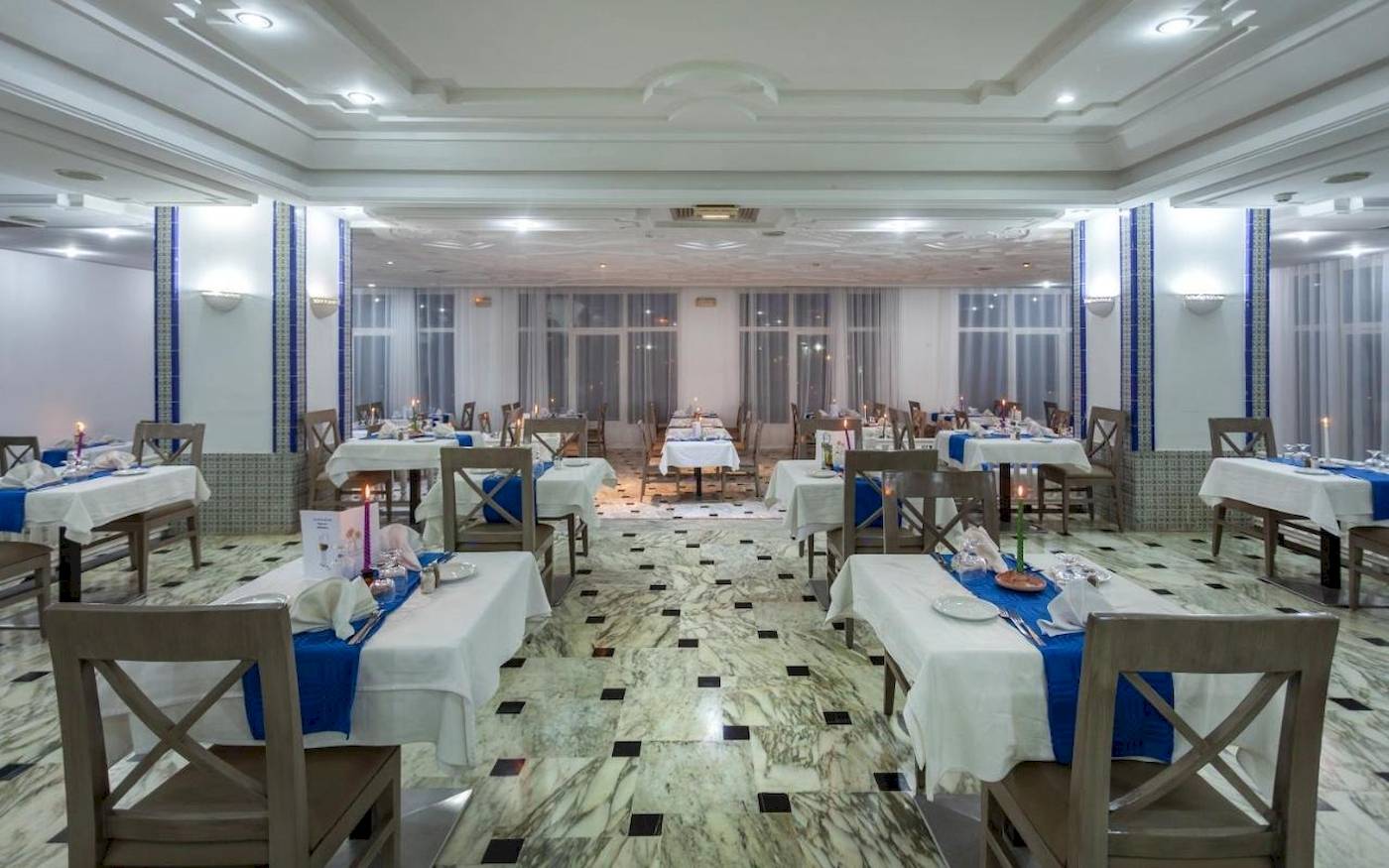 Innenansicht des Restaurants im Djerba Holiday Beach Hotel mit gedeckten Tischen und Stühlen.
