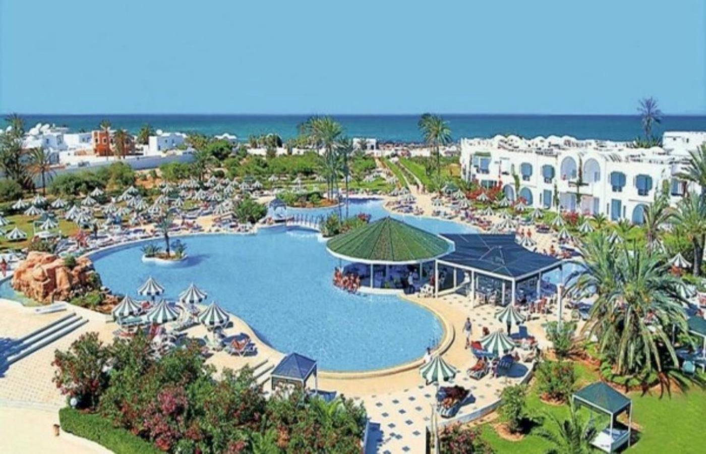 Luftaufnahme des Djerba Holiday Beach Resorts mit Pool, Sonnenschirmen und Hotelgebäuden am Meer