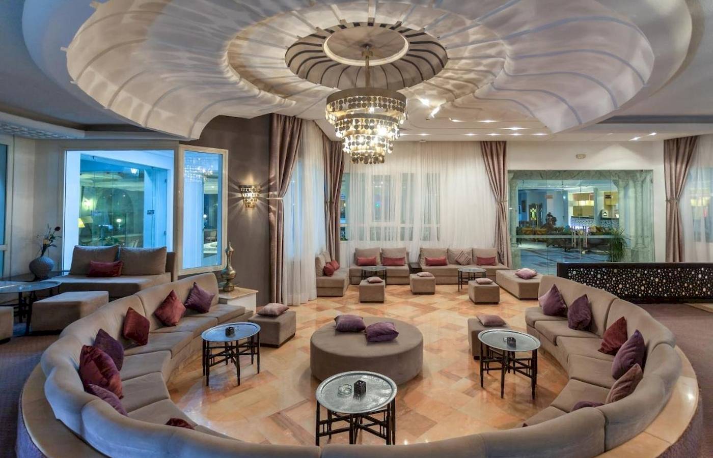 Lobby des Djerba Holiday Beach Hotels mit großen Sofas, Tischen und einer beeindruckenden Deckenleuchte.