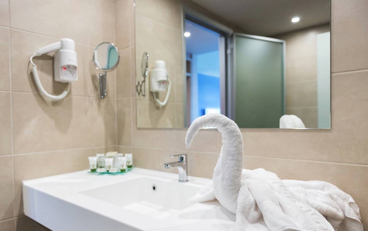 Badezimmer im Irene Palace Beach Resort mit Waschbecken, Handtüchern und Haartrocknern.