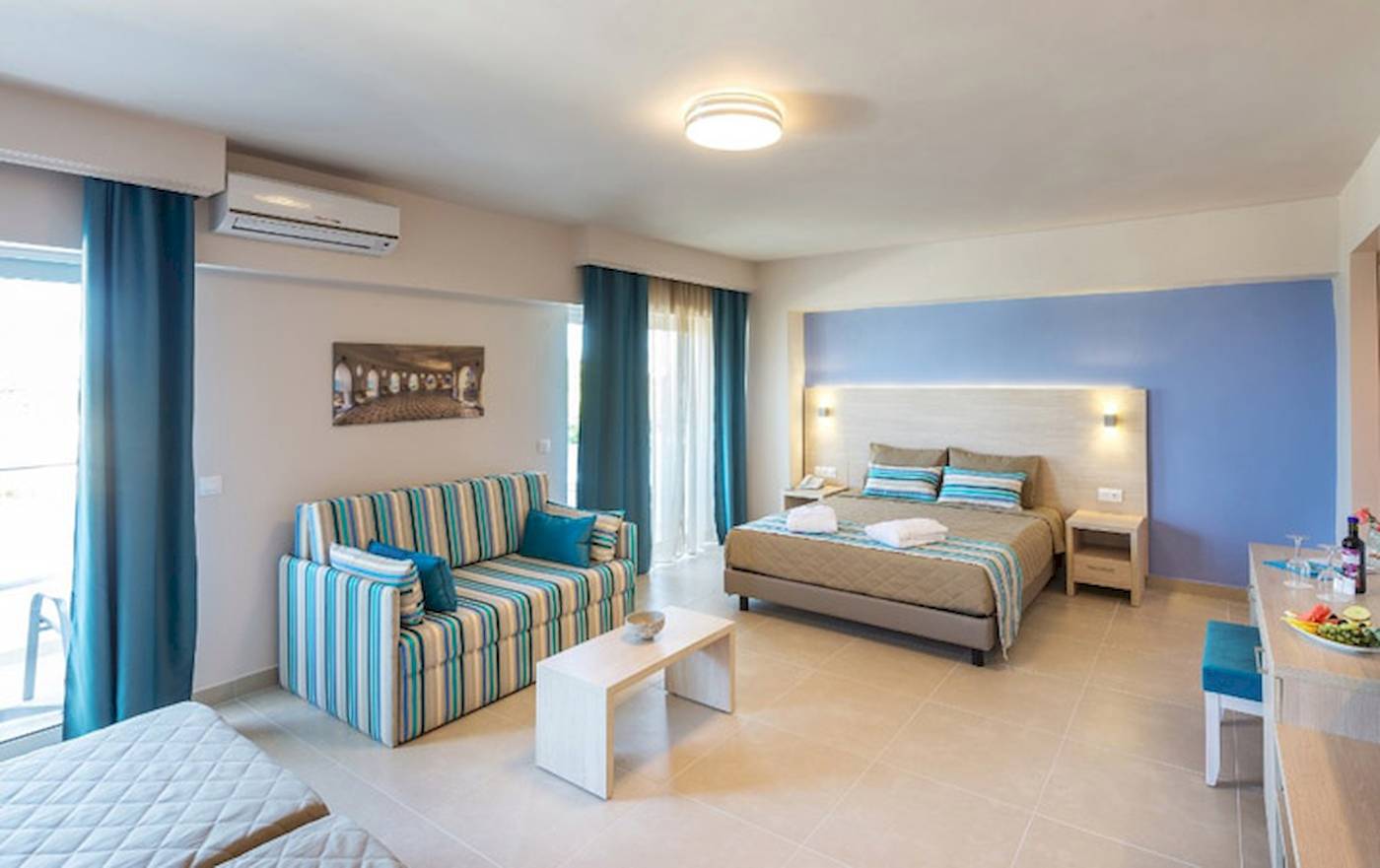 Innenansicht eines Zimmers im Irene Palace Beach Resort mit einem Bett, einem Sofa und einem Tisch.