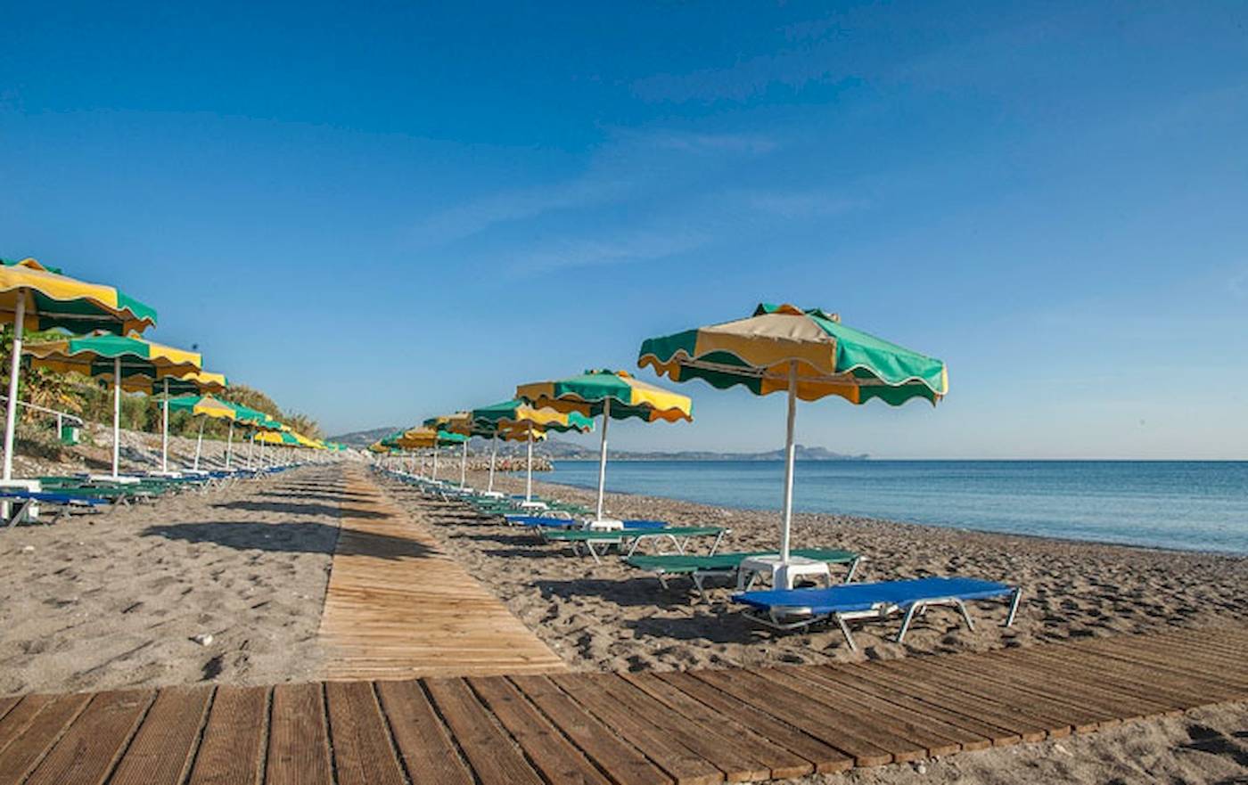 Reihe von Sonnenliegen und Sonnenschirmen am Strand des Irene Palace Beach Resorts