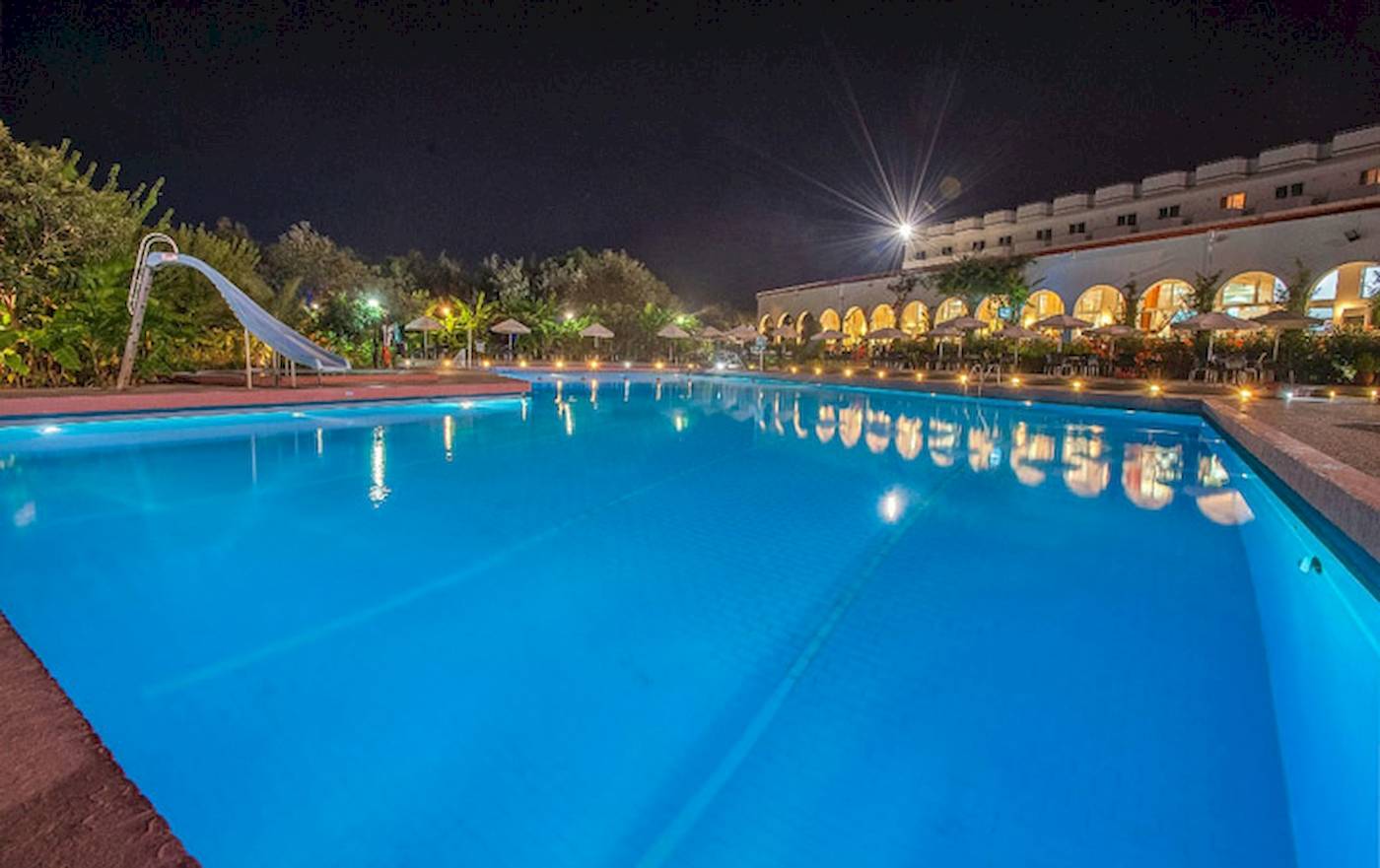 Nachtansicht des Swimmingpools im Irene Palace Beach Resort mit blauem Wasser und leuchtenden Lichtern.