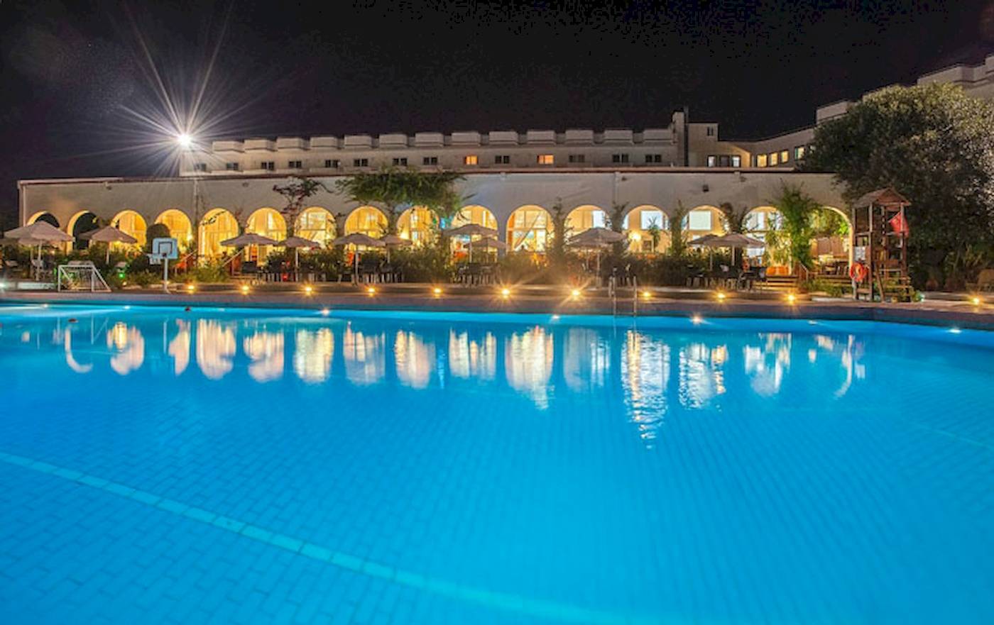 Nachtansicht des Irene Palace Beach Resorts mit großem Pool und beleuchteten Gebäuden