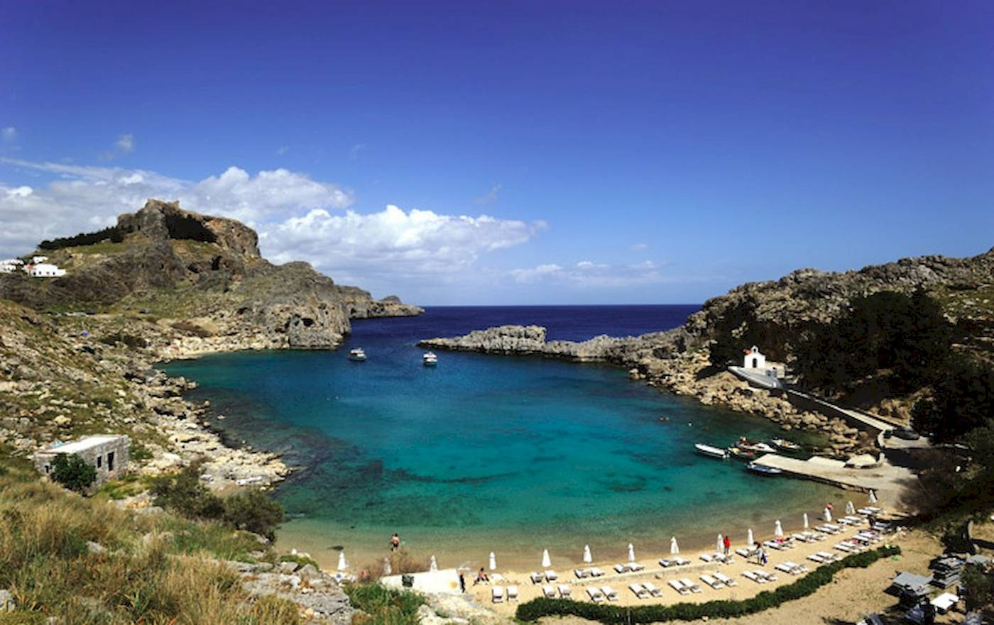 Landschaftsfoto des Irene Palace Beach Resorts mit türkisfarbenem Wasser und weißen Liegestühlen.