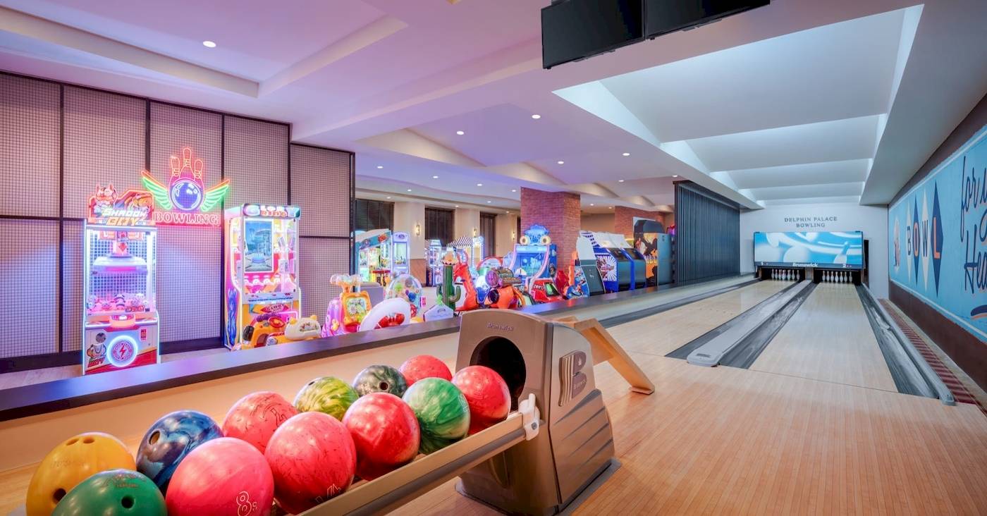 Bowlinghalle im Delphin Palace Hotel mit bunten Bowlingkugeln und Arcade-Spielautomaten.