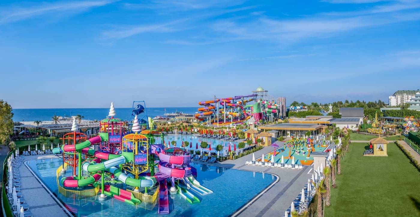 Außenansicht des Delphin Palace Wasserparks mit bunten Wasserrutschen und einem großen Pool.