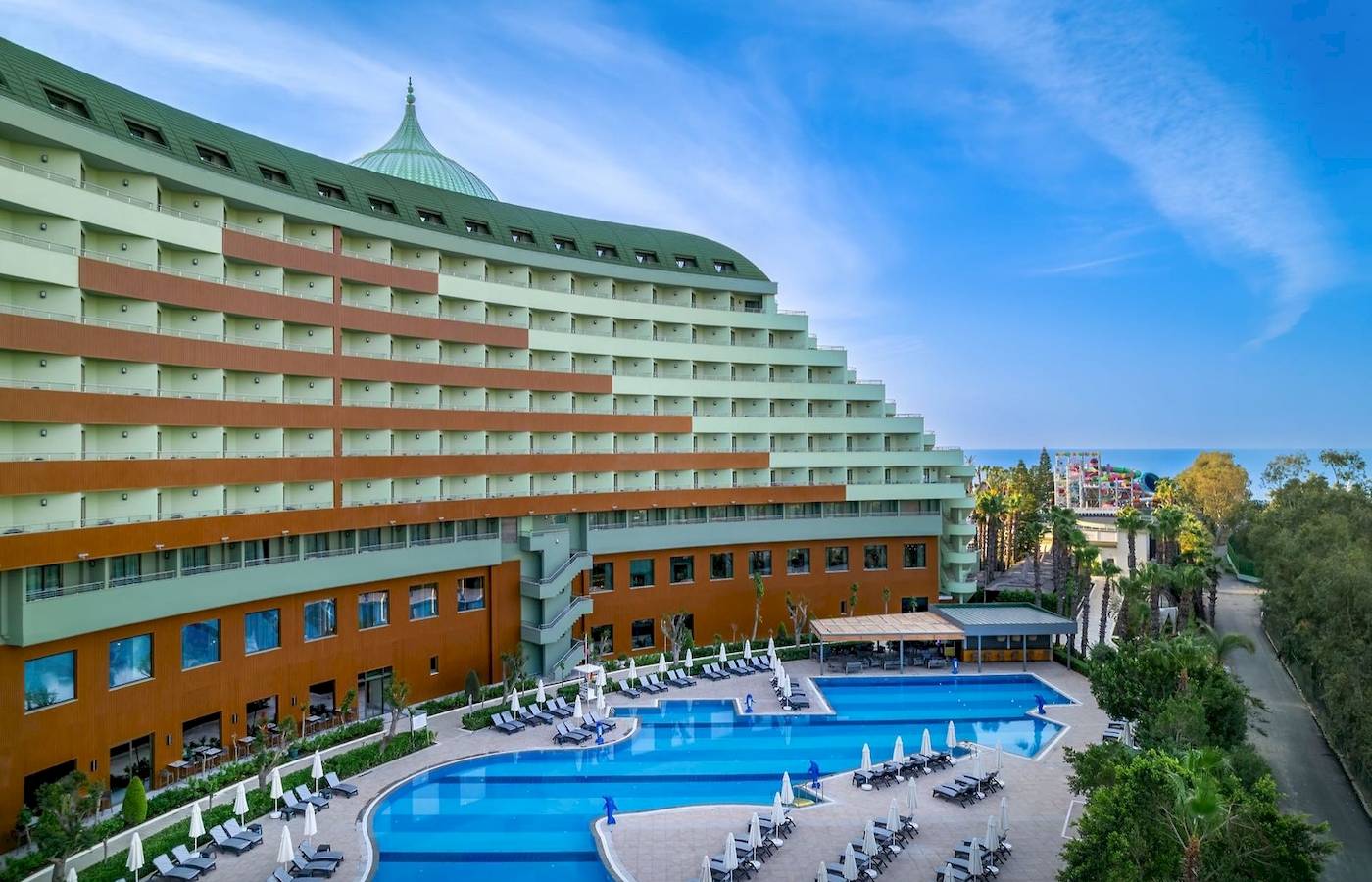Außenansicht des Delphin Palace Hotels mit Swimmingpool und Sonnenliegen.