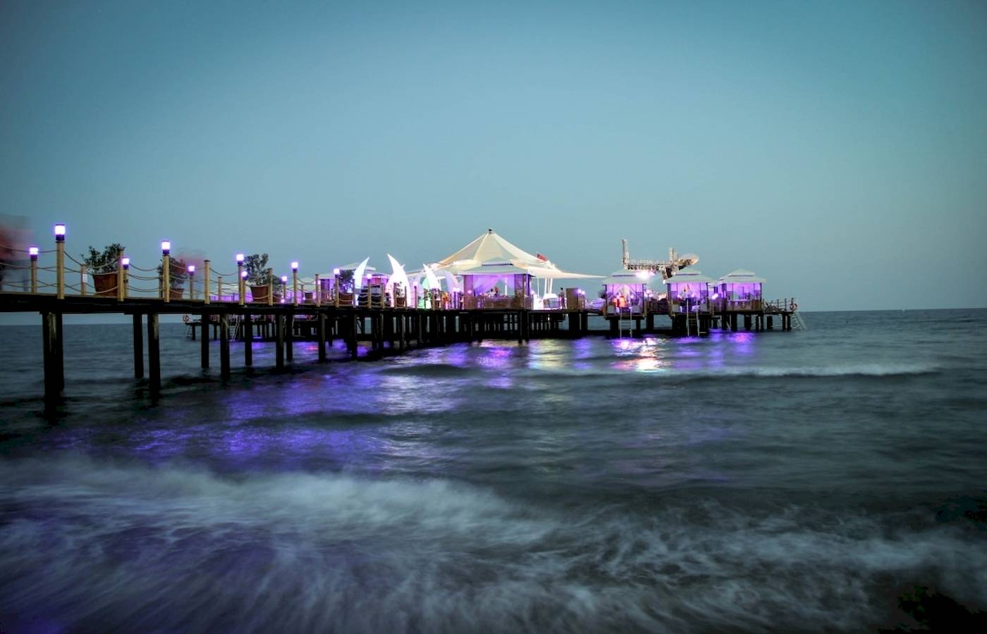 Beleuchteter Pier des VONRESORT Golden Coast bei Nacht mit weißen Zelten und blauen Lichtern.