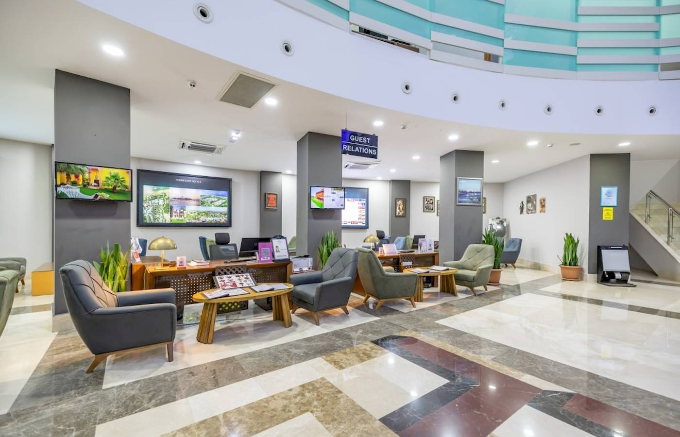 Empfangshalle des VONRESORT Golden Coast mit modernem Design, Sitzbereichen, Tischen, Pflanzen und Monitoren.