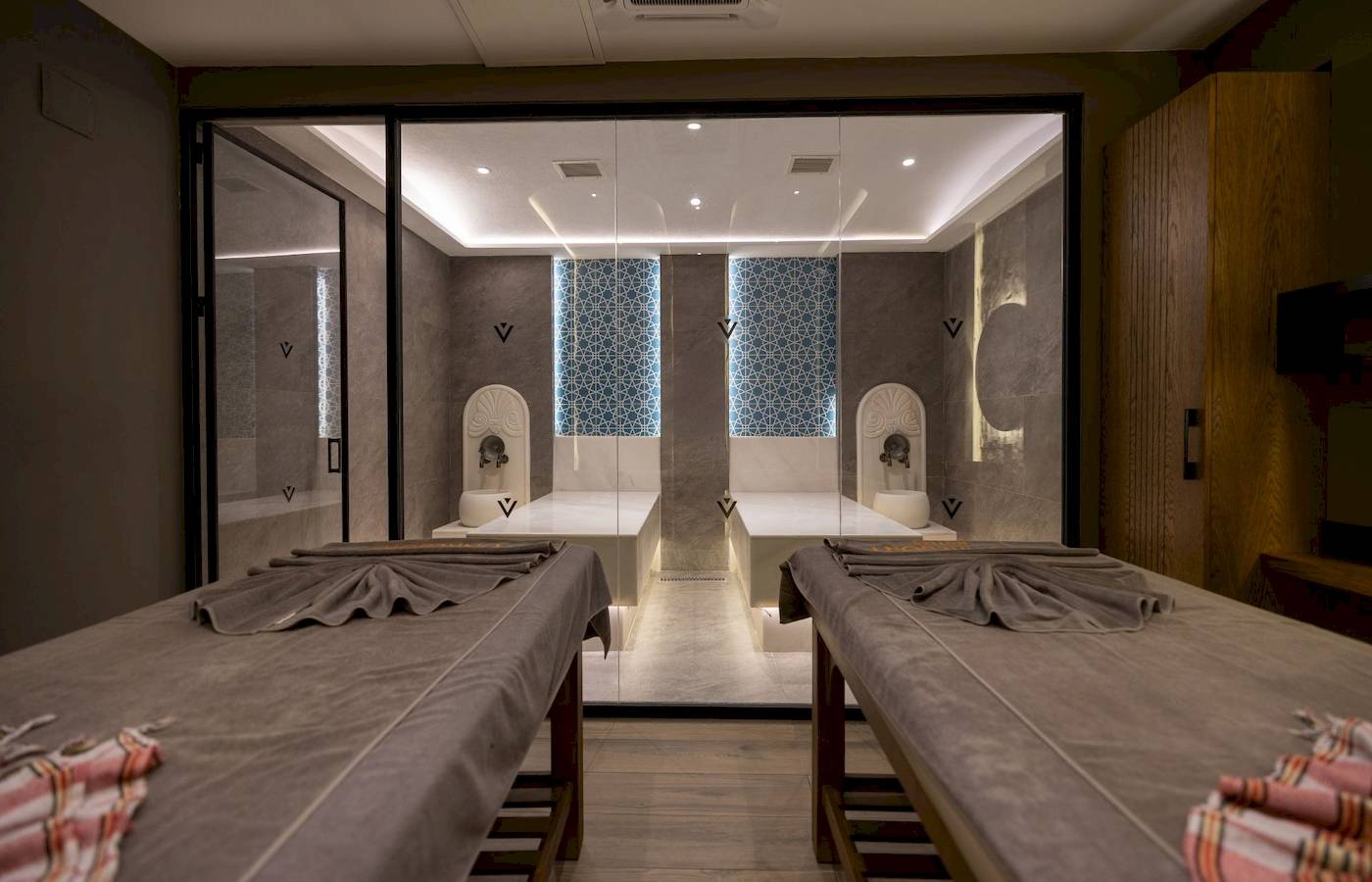 Spa-Behandlungsraum im VONRESORT Golden Coast mit zwei Massagetischen und Glaswänden.