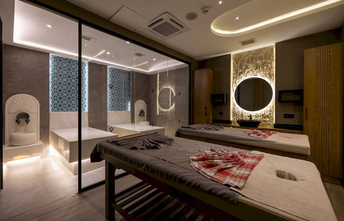 Spa-Behandlungsraum im VONRESORT Golden Coast mit zwei Massagetischen und Glaswänden.