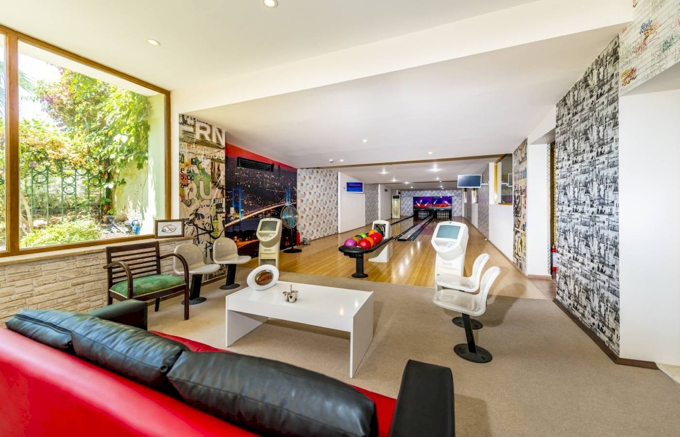 Bowlinghalle im VONRESORT Golden Coast mit Bowlingbahnen, Sitzmöbeln und einem Fenster mit Gartenblick.