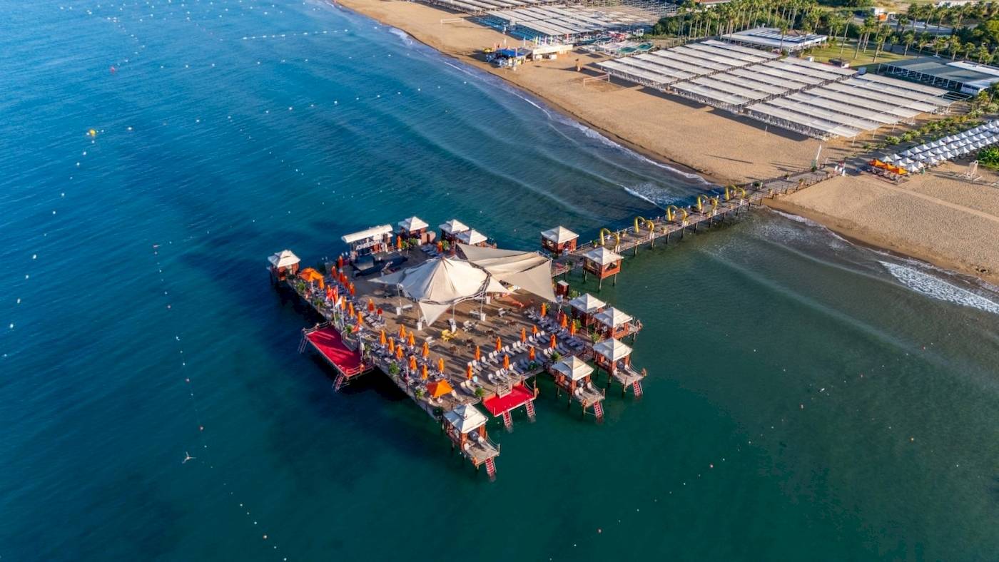 Luftaufnahme des VONRESORT Golden Coast mit mehreren Pavillons und Sonnenschirmen am Meer.