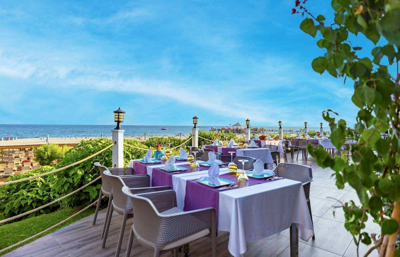 Außenterrasse des VONRESORT Golden Coast mit Tischen und Stühlen, Blick auf den Strand