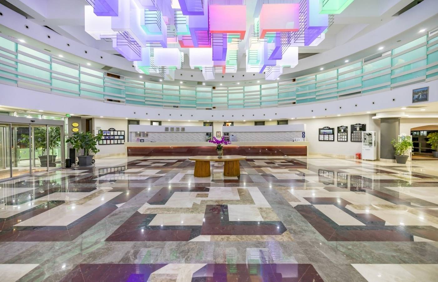 Empfangsbereich des VONRESORT Golden Coast mit farbenfroher Deckenbeleuchtung und Marmorboden.