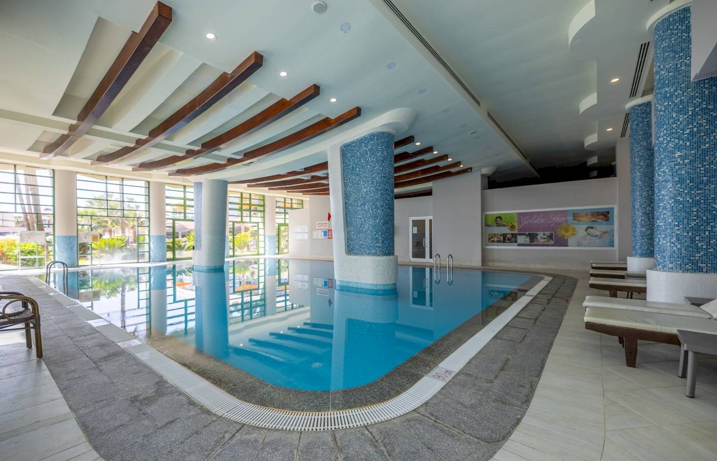 Innenpool des VONRESORT Golden Coast mit blauen Säulen und Sonnenliegen.