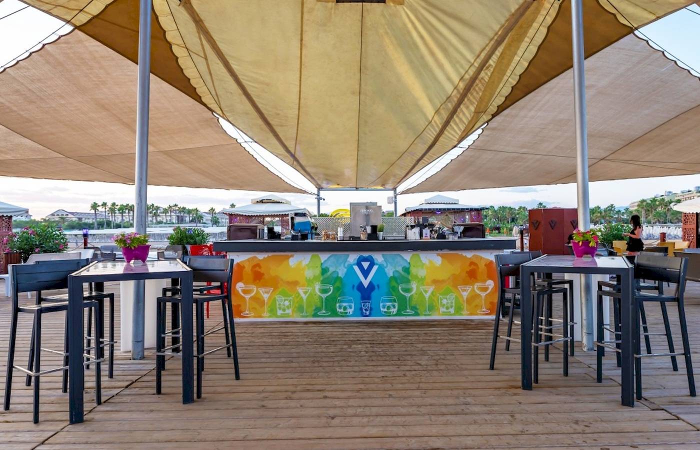 Barbereich des VONRESORT Golden Coast mit bunter Wand und Tischen und Stühlen unter einem Sonnensegel.