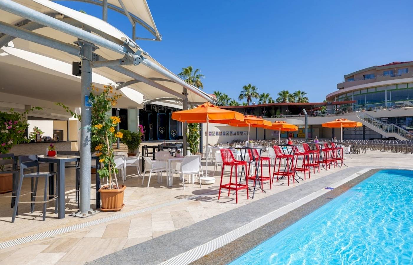 Außenbereich des VONRESORT Golden Coast mit Tischen, Stühlen und Sonnenschirmen am Pool