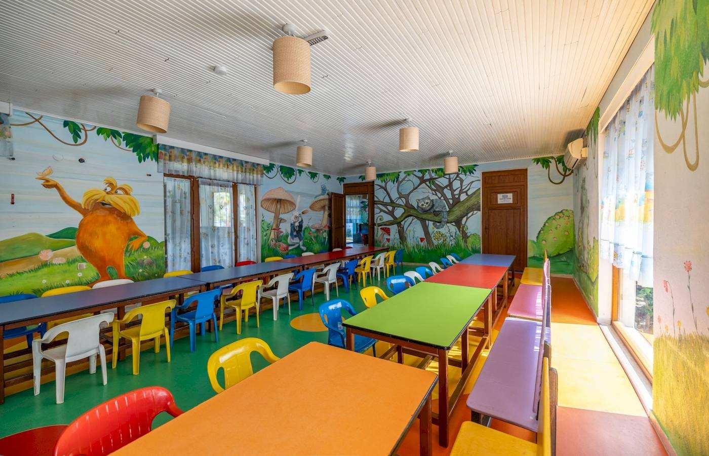 Vonresort Golden Coast Kinderzimmer mit bunten Tischen und Stühlen und illustrierten Wänden.