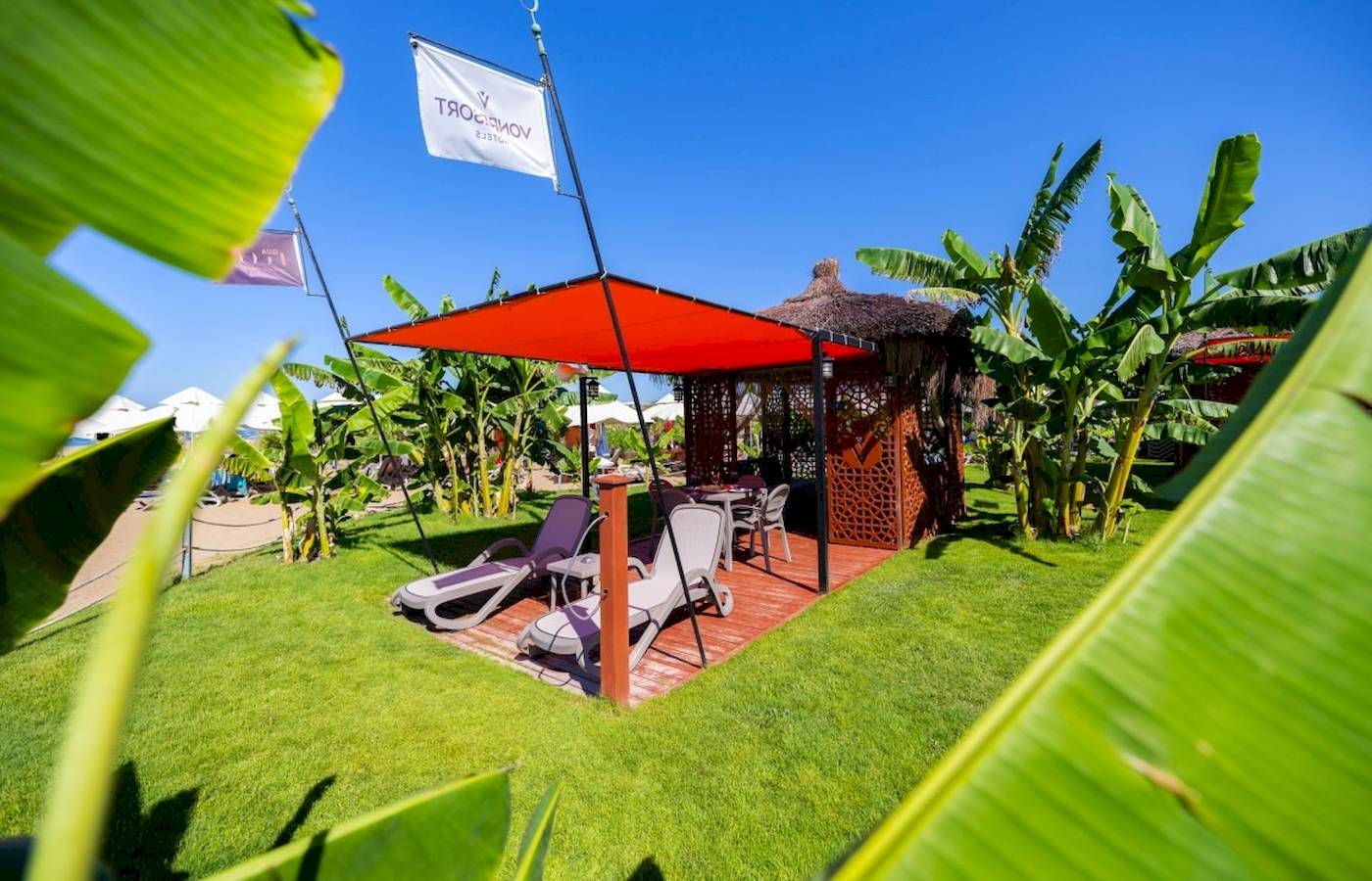 Außenbereich des VONRESORT Golden Coast mit einer Terrasse und Liegestühlen unter einem roten Baldachin.