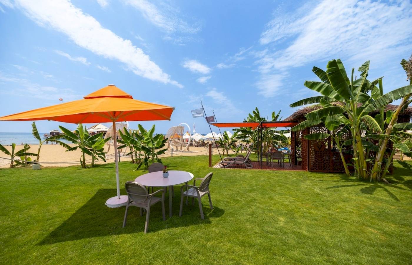 Außenbereich des VONRESORT Golden Coast mit Tisch, Stühlen und Sonnenschirm am Strand