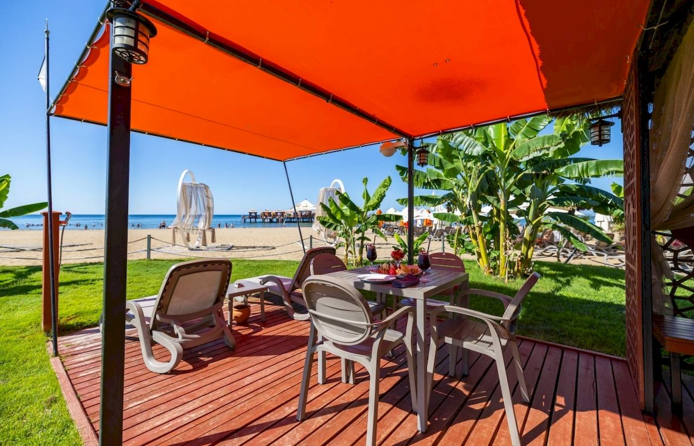 Terrasse des VONRESORT Golden Coast mit Esstisch und Sonnenschirm am Strand
