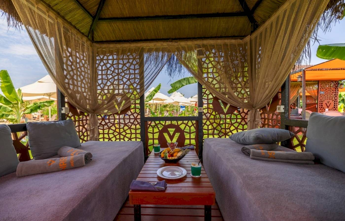 Lounge-Bereich im VONRESORT Golden Coast mit zwei Betten, Kissen und einem Tisch mit Obst.