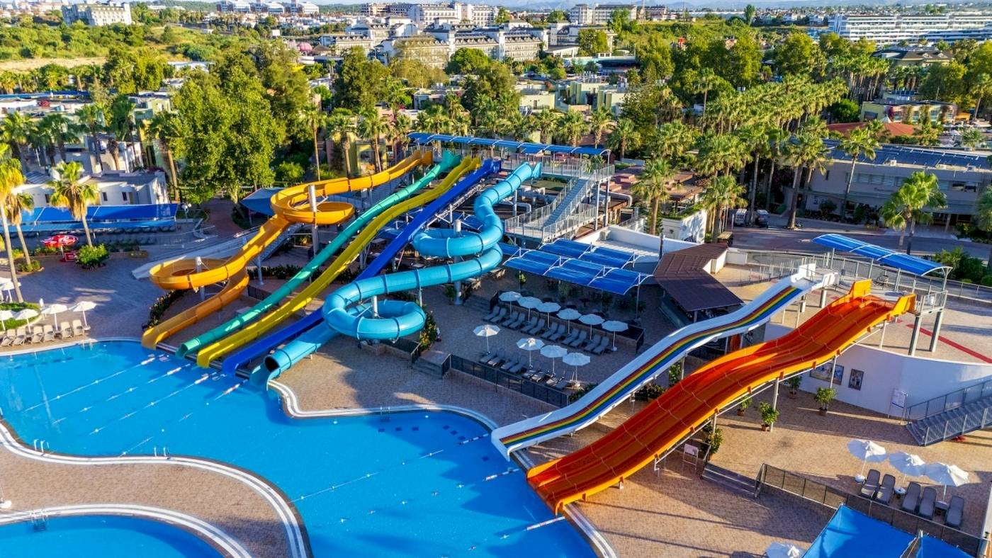 Luftaufnahme des Wasserparks im VONRESORT Golden Coast mit bunten Wasserrutschen und Sonnenschirmen.