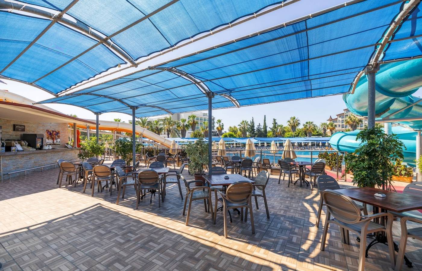 Terrasse des VONRESORT Golden Coast mit Tischen, Stühlen und blauen Markisen.
