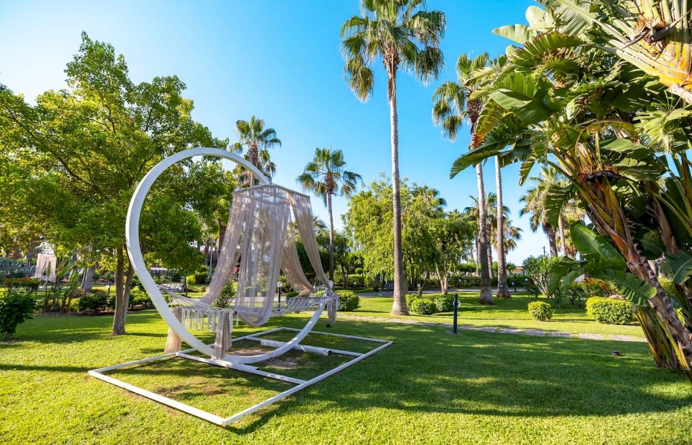 Ein Garten des VONRESORT Golden Coast mit einer weißen Hängematte und umliegenden Bäumen.