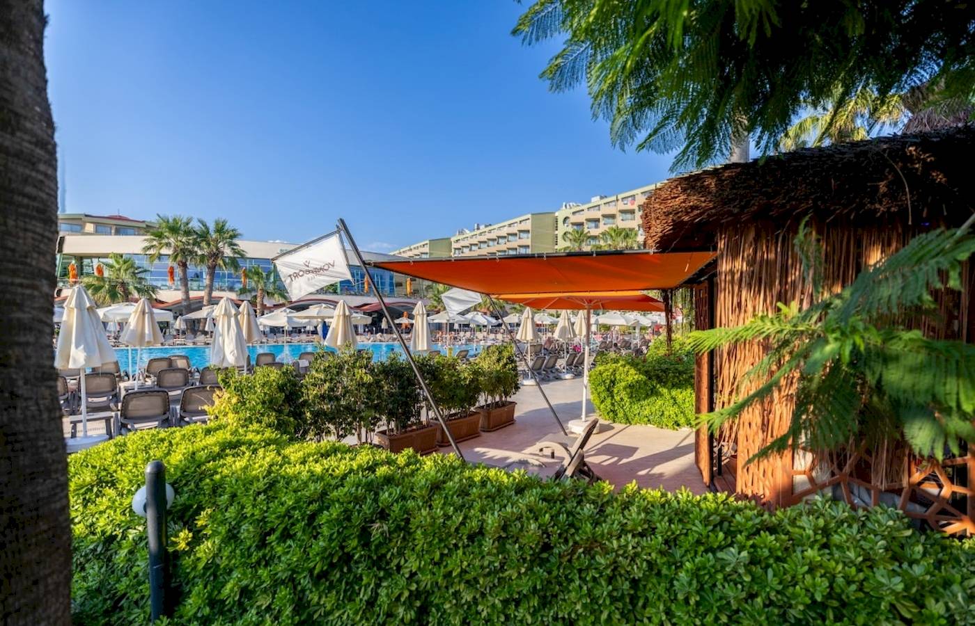 Außenbereich des VONRESORT Golden Coast mit Pool, Sonnenschirmen und Liegestühlen.