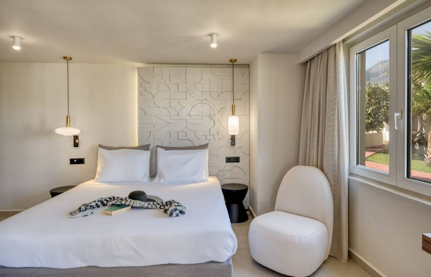 Georgioupolis Resort Aquapark & SPA Zimmer mit Bett, weißem Stuhl und Fenster mit Aussicht auf den Berg.