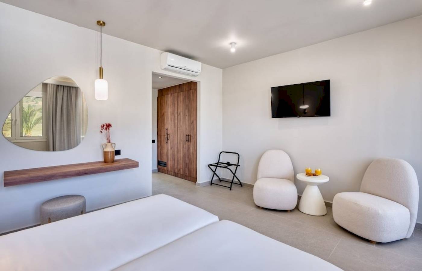 Innendesign eines Zimmers im Georgioupolis Resort Aquapark & SPA mit weißen Möbeln und einer Terrasse.