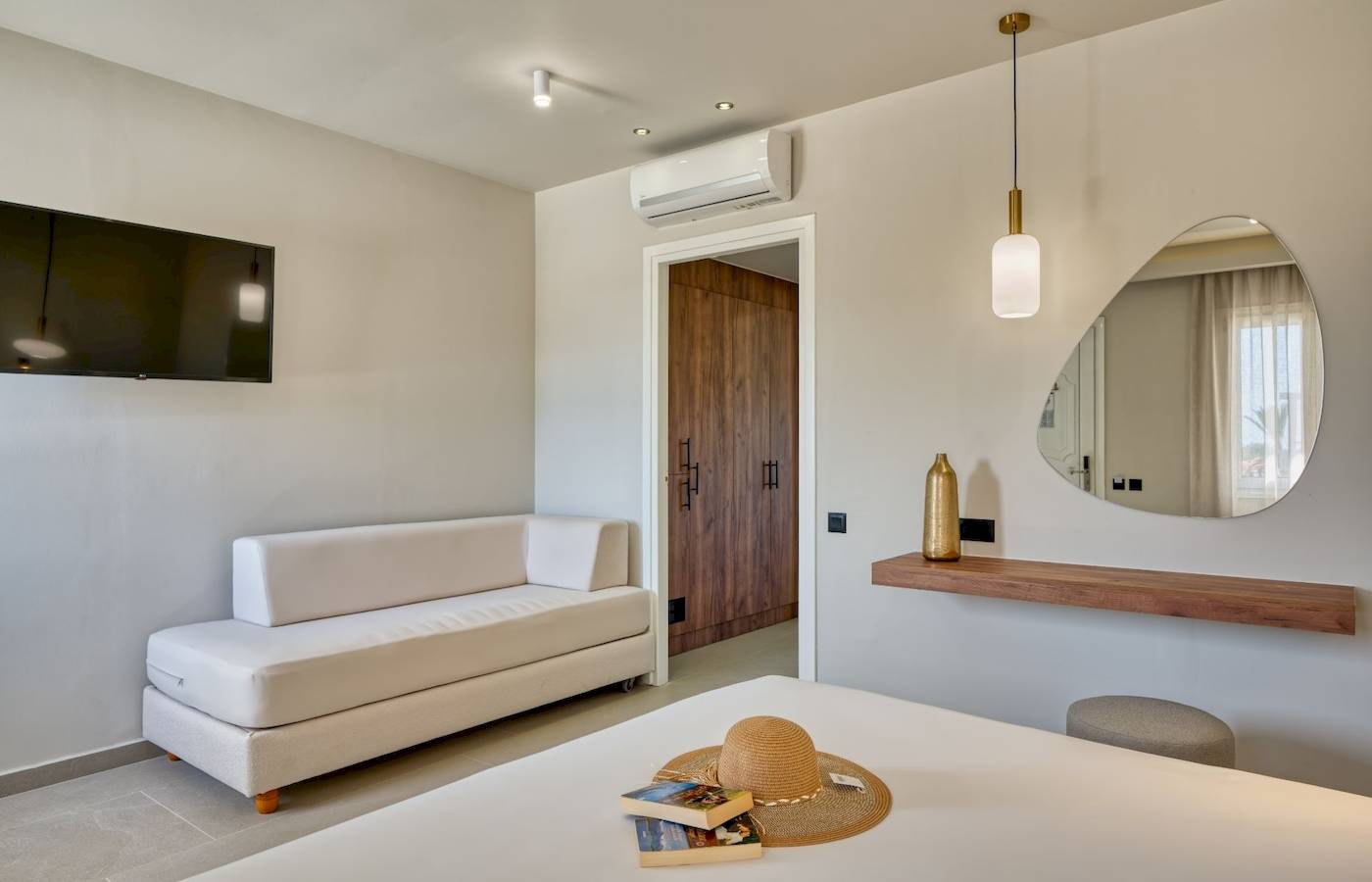 Innenansicht eines Zimmers im Georgioupolis Resort Aquapark & SPA mit Bett, Sofa und Fernseher.