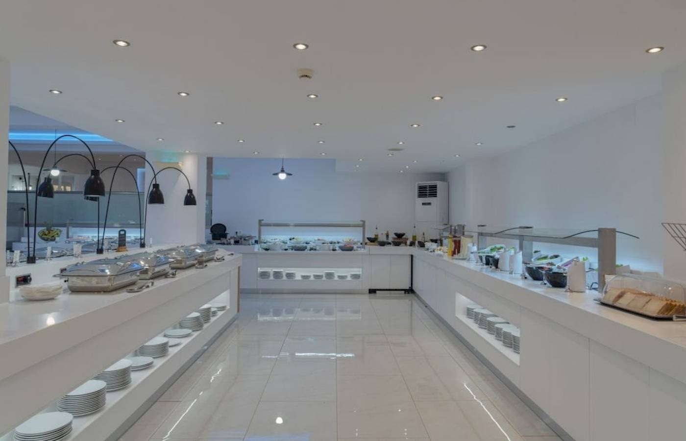 Innenansicht des Restaurants im Georgioupolis Resort Aquapark & SPA Hotel mit weißen Tischen und Buffets.