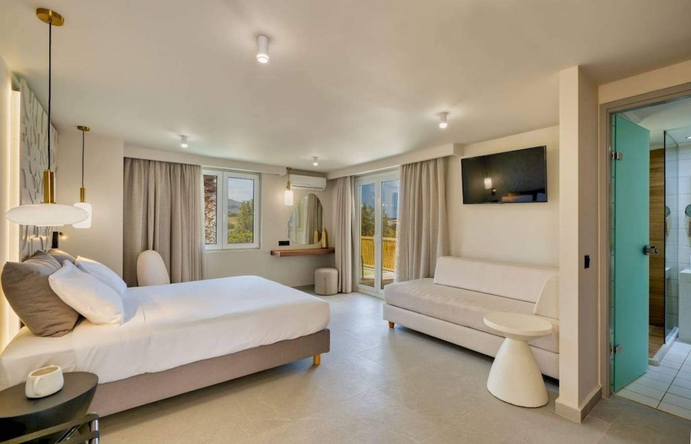 Innenansicht eines Hotelzimmers im Georgioupolis Resort Aquapark & SPA mit Bett, Sofa, Fernseher und Dusche