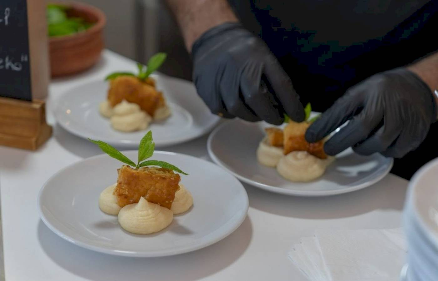 Eine Person bereitet Gerichte auf weißen Tellern im Georgioupolis Resort Aquapark & SPA vor.