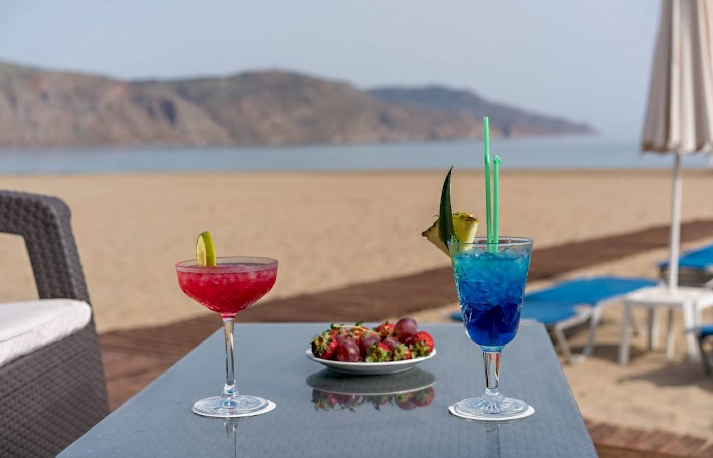 Zwei Cocktails mit Strohhalmen und Obstteller auf einem Tisch am Strand im Georgioupolis Resort.